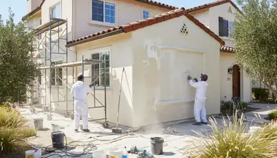 Painter preparing exterior wall for repainting on San Mateo, CA home during professional surface prep